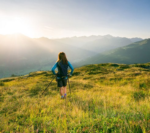 Wanderin mit Stöcken auf einer Almwiese auf der Schlossalm mit Blick auf das Gasteinertal.