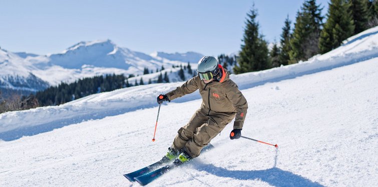 Skifahrerin beim Carven auf der Schlossalm im Gasteinertal mit Blick auf verschneite Alpen und Tannenwald