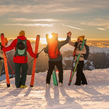 Skitourengeher freuen sich im Sonnenaufgang 