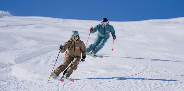 Skifahrer und Skifahrerin beim Carven auf der Schlossalm im Gasteinertal auf frisch präparierter Piste