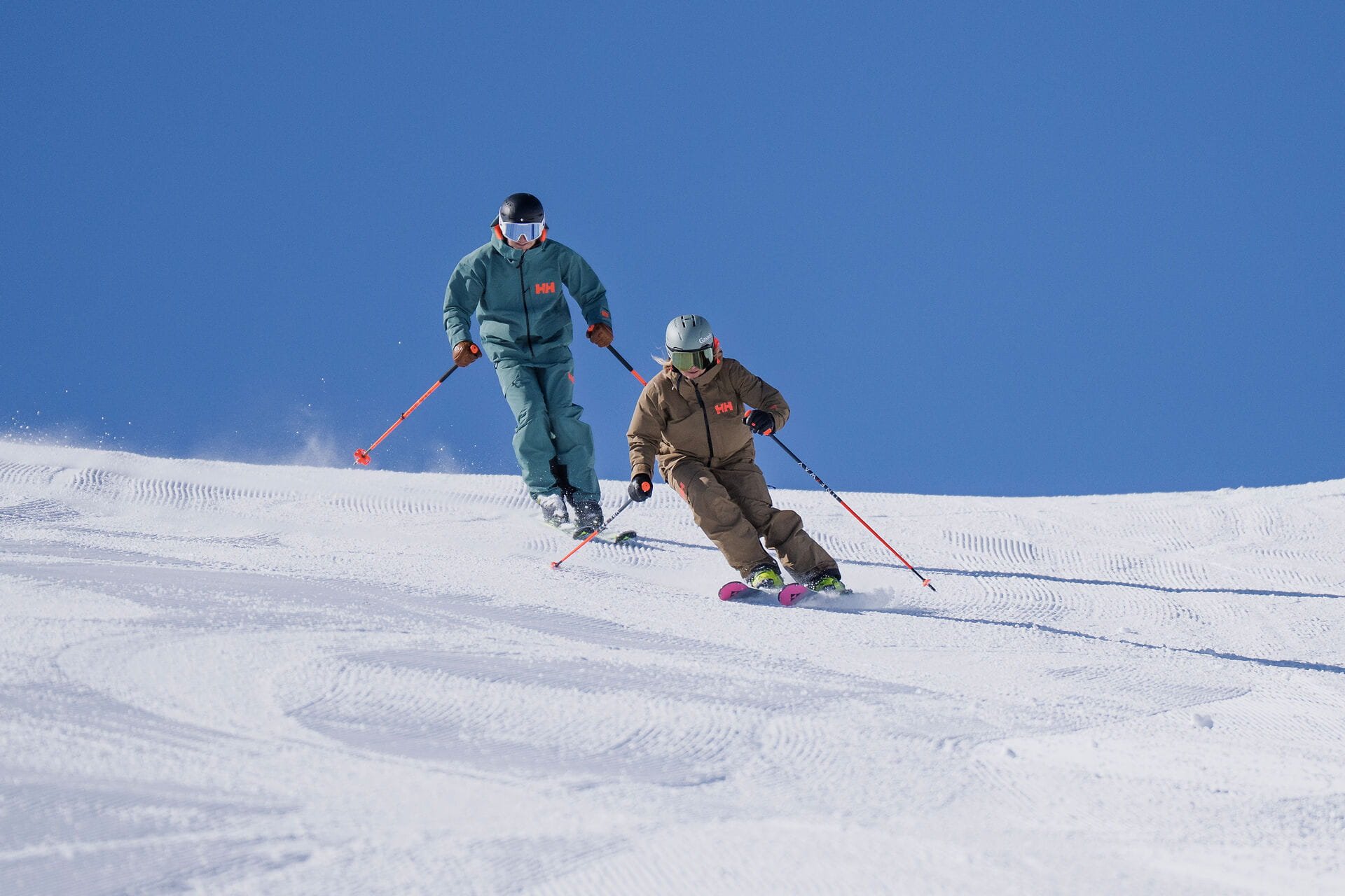 Skifahrer und Skifahrerin auf der Schlossalm im Gasteinertal vor blauem Himmel auf verschneitem Hang