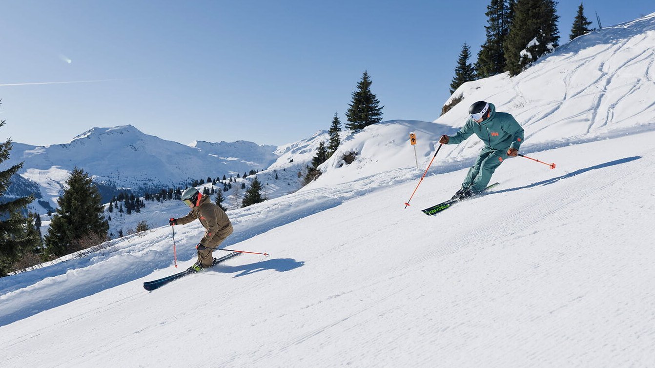 Skifahrer und Skifahrerin auf der Schlossalm im Gasteinertal mit Blick auf verschneite Berge und Winterlandschaft