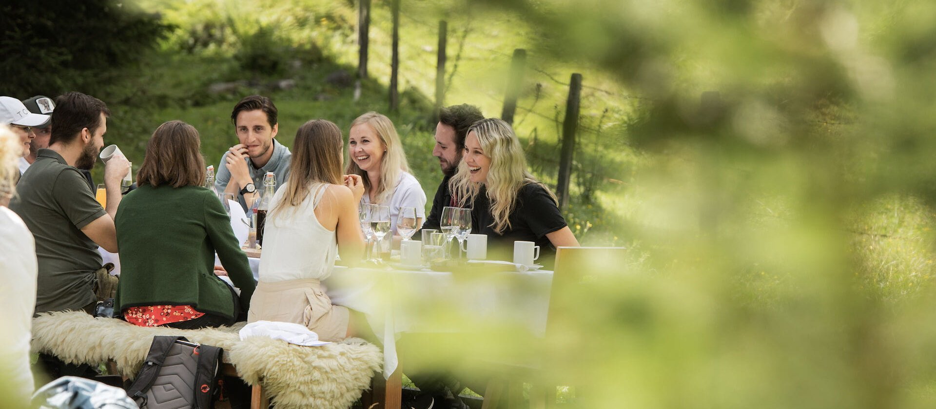 Freunde genießen eine entspannte Zeit im Freien, während sie an einem Tisch mit Essen und Getränken plaudern.
