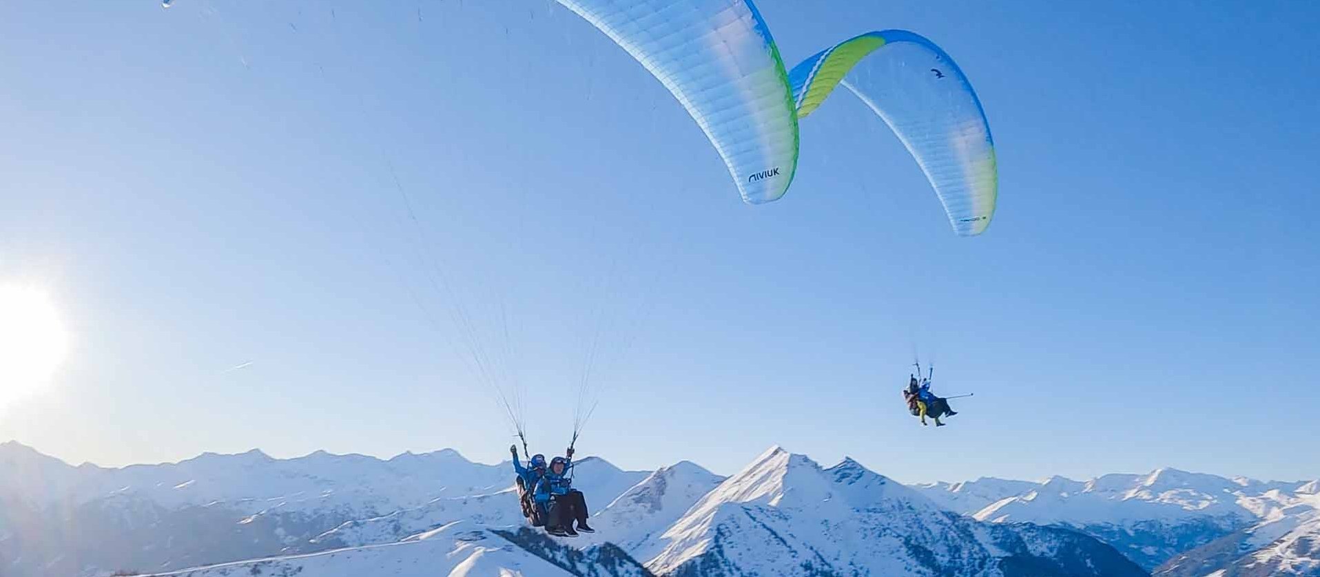 Zwei Paragleiter über den verschneiten Bergen