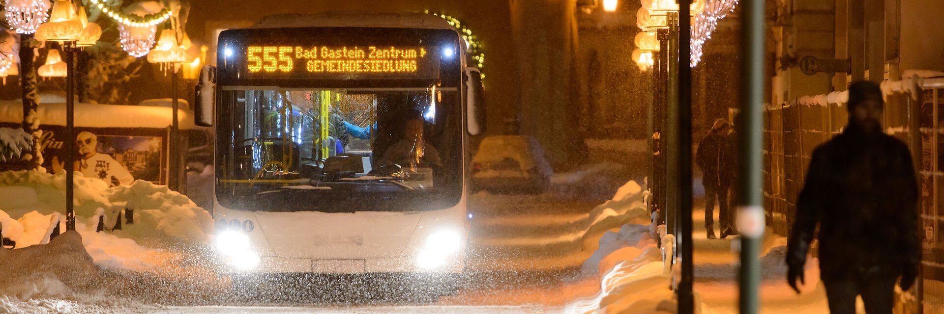 Der Citybus fährt bei Schneefall durch das abendliche Bad Gastein