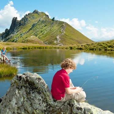 Wanderer auf der Schlossalm in Bad Hofgastein beim Pausieren am Bergsee