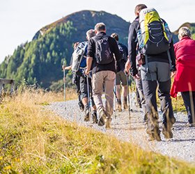 Eine Gruppe Wanderer, mit Rucksack und Wanderstöcken unterwegs Richtung Berge in Gastein.