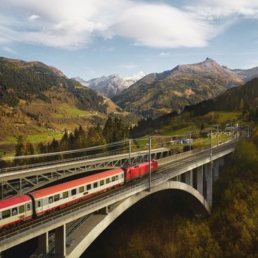 Zug fährt über eine Eisenbahnbrücke auf dem Weg in das Gasteinertal