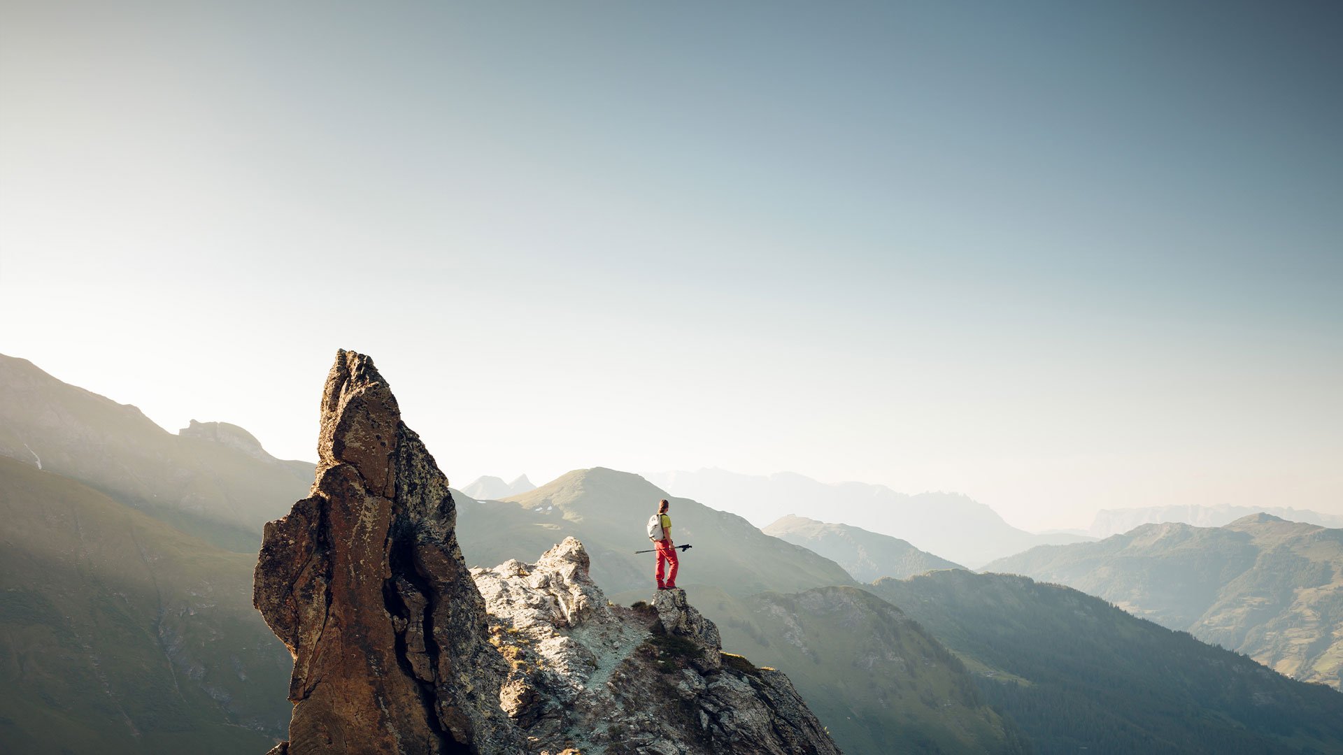Wanderer steht auf schmalem Felsgrat mit Blick auf die Berglandschaft im Gasteinertal